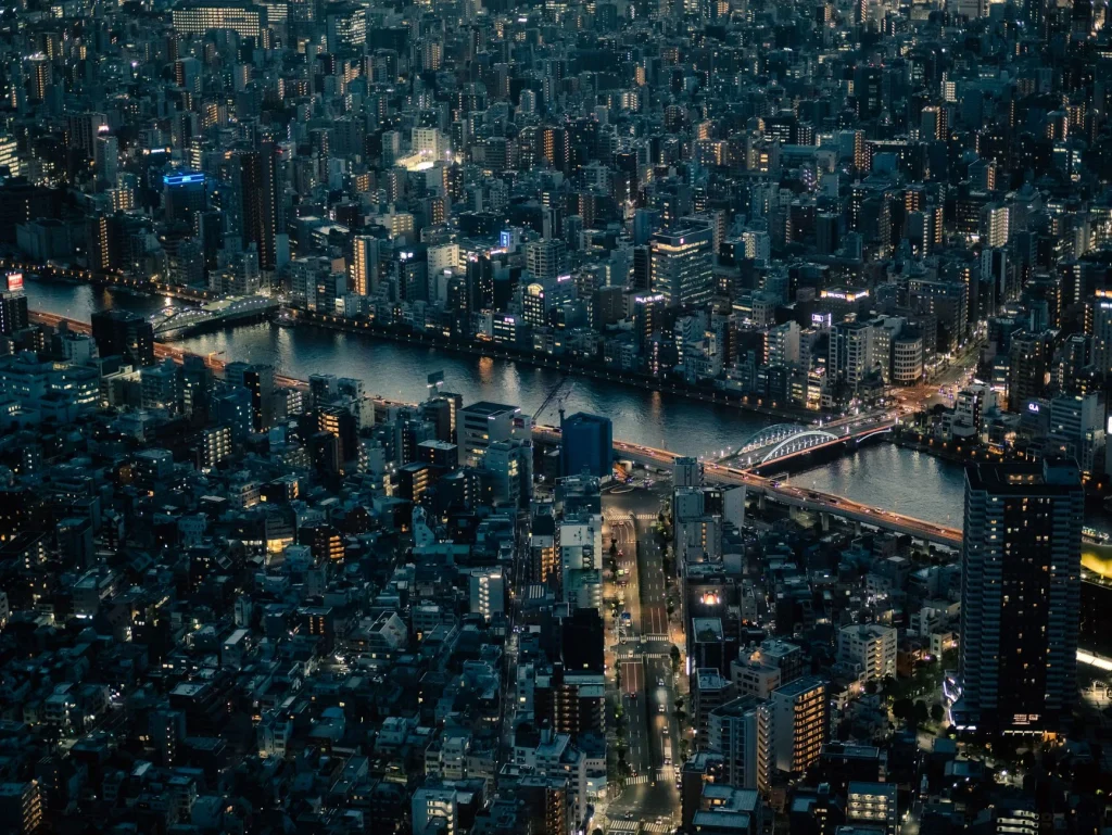 Panorámica nocturna de Tokio con rascacielos y un templo junto al río